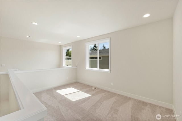 spare room featuring light colored carpet, recessed lighting, and baseboards