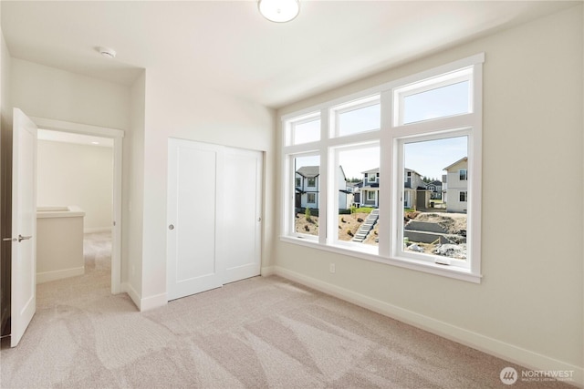 unfurnished bedroom featuring carpet flooring, a closet, and baseboards