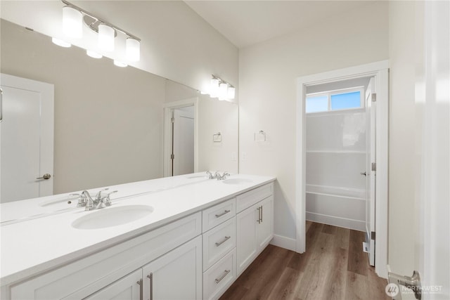 full bath featuring wood finished floors, double vanity, and baseboards