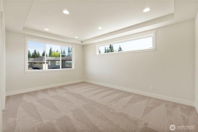 unfurnished room featuring a tray ceiling, baseboards, recessed lighting, and light carpet