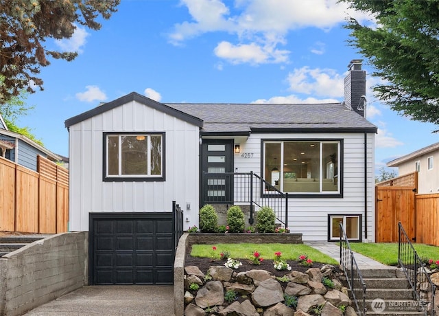 4257 33rd Ave W, Seattle, WA 98199 - view of front facade with a garage, fence, a chimney, roof with shingles, and board and batten siding