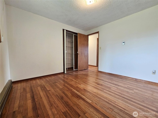 810 H St, Forks, WA 98331 - spare room featuring baseboard heating, hardwood / wood-style floors, a textured ceiling, and baseboards