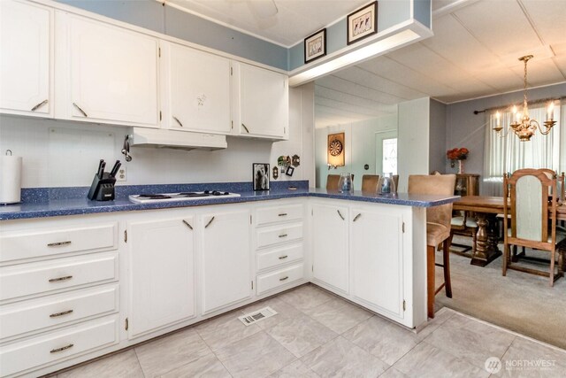 2101 S 324th St Unit 136, Federal Way, WA 98003 - kitchen with a chandelier, dark countertops, white gas stovetop, white cabinets, and a kitchen breakfast bar