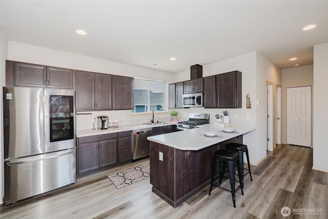 2450 Zeeden Way, Bremerton, WA 98310 - kitchen featuring stainless steel appliances, dark brown cabinetry, a breakfast bar, light wood-style flooring, and a sink