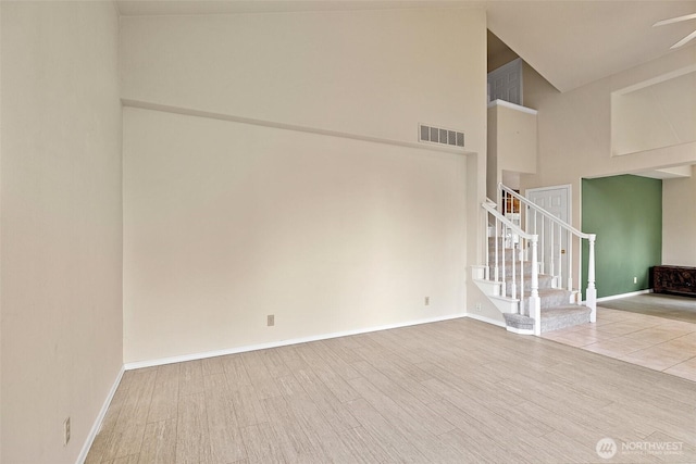 12015 SE 312th Pl Unit 7D, Auburn, WA 98092 - unfurnished room featuring a towering ceiling, stairway, ceiling fan, wood finished floors, and baseboards