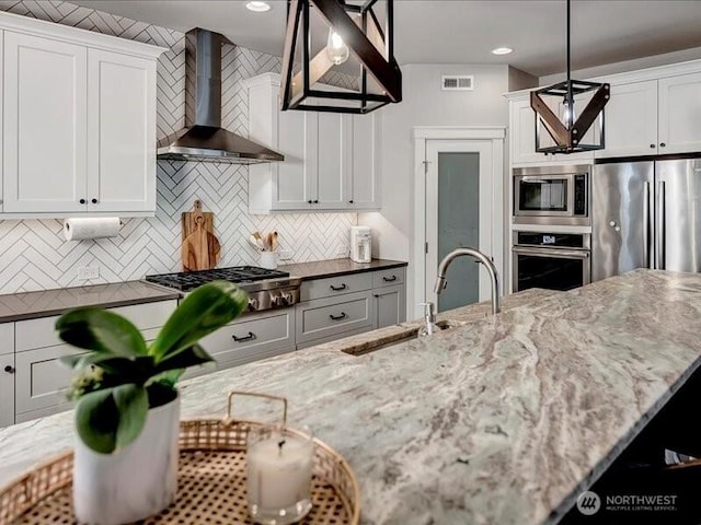 11550 174th Ave NE, Redmond, WA 98052 - kitchen with appliances with stainless steel finishes, wall chimney range hood, decorative backsplash, dark stone countertops, and white cabinetry