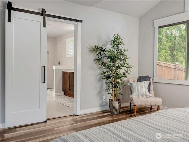 11550 174th Ave NE, Redmond, WA 98052 - bedroom with wood finished floors, a barn door, connected bathroom, vaulted ceiling, and baseboards