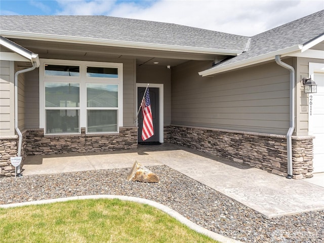 2611 Paisley St SE, East Wenatchee, WA 98802 - view of exterior entry featuring stone siding, an attached garage, and roof with shingles
