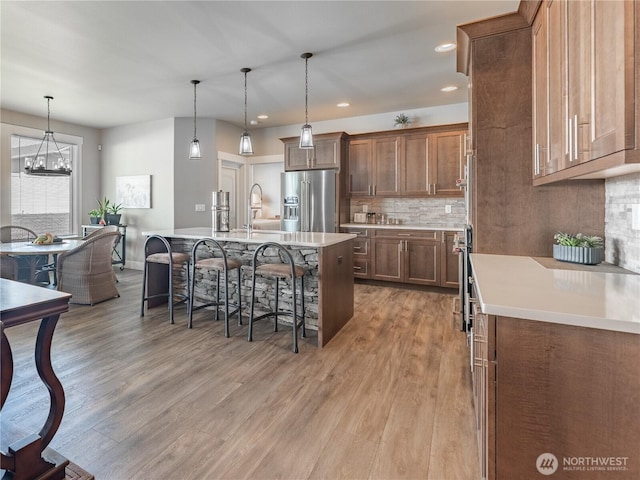 2611 Paisley St SE, East Wenatchee, WA 98802 - kitchen featuring high quality fridge, light wood-style floors, a breakfast bar area, light countertops, and decorative backsplash