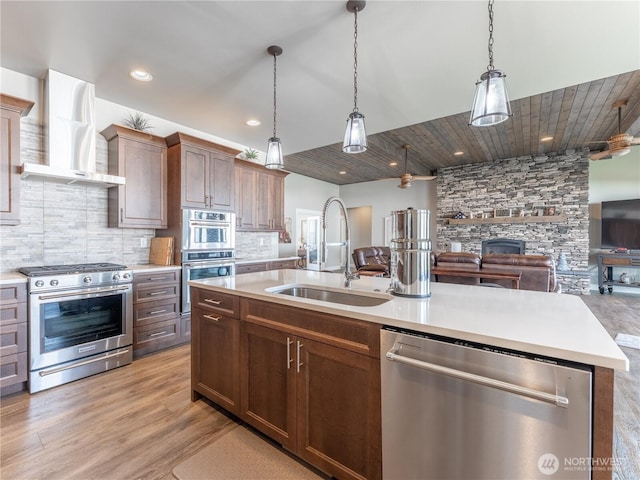 2611 Paisley St SE, East Wenatchee, WA 98802 - kitchen with stainless steel appliances, wall chimney range hood, a sink, open floor plan, and light countertops