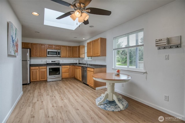 184 Frigate St NW, Ocean Shores, WA 98569 - kitchen featuring appliances with stainless steel finishes, a skylight, dark countertops, baseboards, and light wood-type flooring