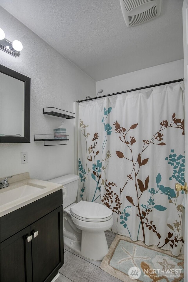184 Frigate St NW, Ocean Shores, WA 98569 - bathroom featuring a textured ceiling, vanity, toilet, and curtained shower