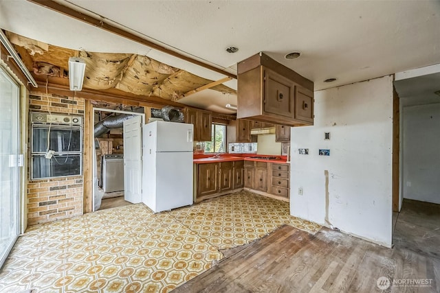 3122 Oas Dr W, University Place, WA 98466 - kitchen with stainless steel appliances, washer / clothes dryer, brown cabinetry, and light floors