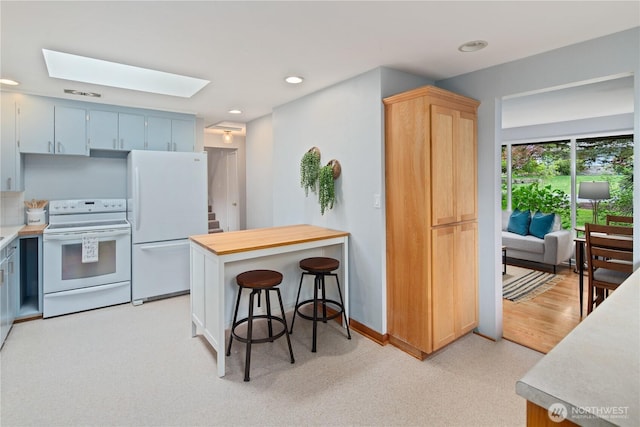 16044 33rd Ave NE, Lake Forest Park, WA 98155 - kitchen featuring white appliances, a skylight, light countertops, recessed lighting, and a breakfast bar area