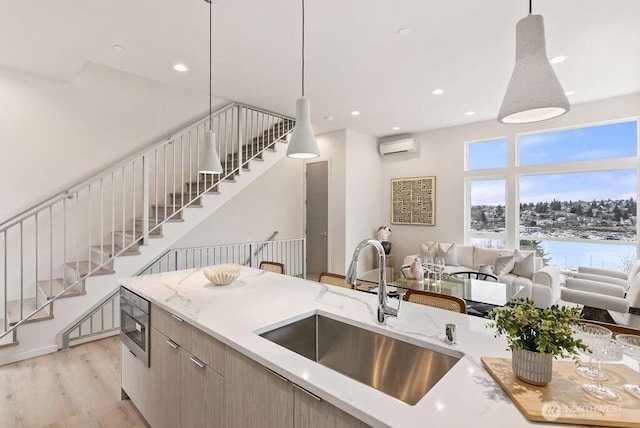 2925 Franklin Ave E Unit B, Seattle, WA 98102 - kitchen with a sink, light wood-style floors, stainless steel microwave, an AC wall unit, and pendant lighting