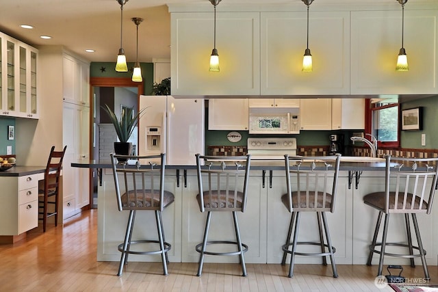 5066 Bayview Rd, Langley, WA 98260 - kitchen featuring white appliances, hanging light fixtures, glass insert cabinets, a kitchen bar, and a sink