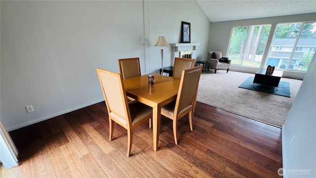 3732 S 254th Pl, Kent, WA 98032 - dining space featuring a fireplace, vaulted ceiling, wood finished floors, and a textured ceiling