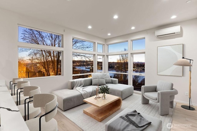 living area with a wall unit AC, light wood-style floors, recessed lighting, plenty of natural light, and a towering ceiling