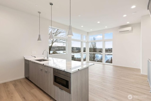 kitchen featuring a sink, a peninsula, a wall mounted AC, light wood finished floors, and baseboards