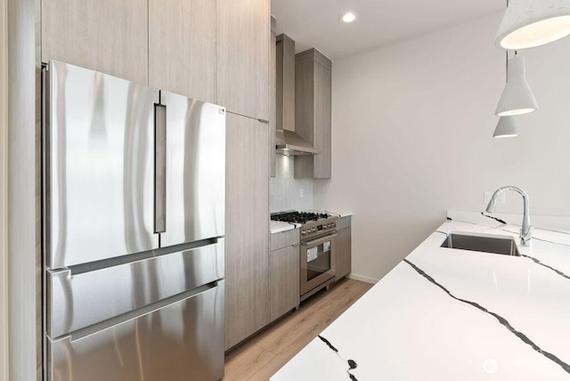 kitchen featuring stainless steel appliances, modern cabinets, wall chimney exhaust hood, a sink, and light countertops