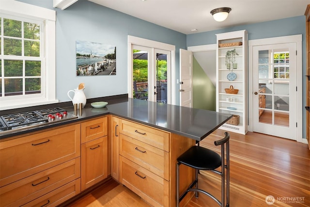 3227 37th Ave S, Seattle, WA 98144 - kitchen featuring light wood finished floors, french doors, stainless steel gas cooktop, a kitchen bar, and dark countertops