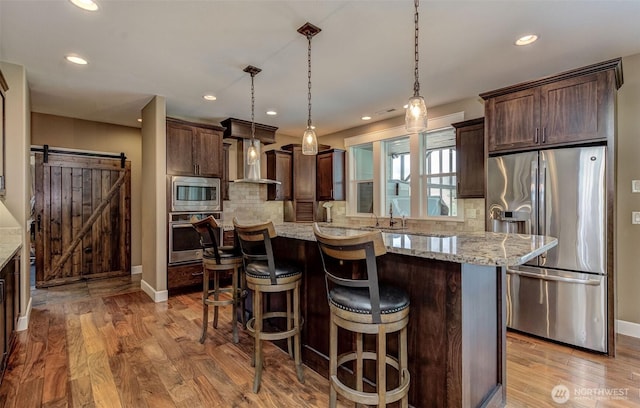 1400 Westpoint Pl, Wenatchee, WA 98801 - kitchen with stainless steel appliances, a barn door, dark brown cabinets, light wood-type flooring, and recessed lighting