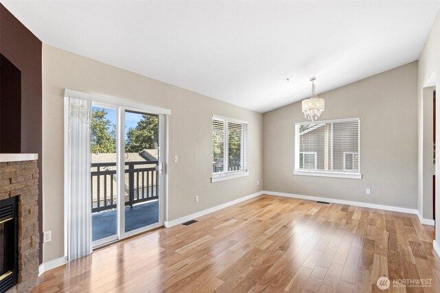 901 E Marine View Dr Unit 201, Everett, WA 98201 - unfurnished dining area featuring a chandelier, vaulted ceiling, light wood-style flooring, a glass covered fireplace, and baseboards