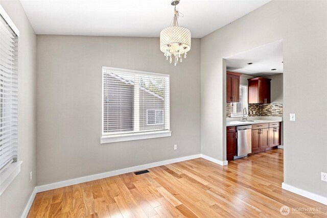 901 E Marine View Dr Unit 201, Everett, WA 98201 - unfurnished dining area featuring light wood-style flooring, plenty of natural light, a chandelier, and baseboards