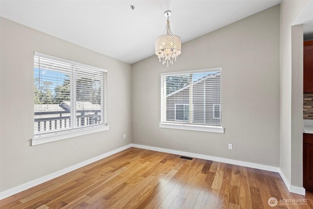 901 E Marine View Dr Unit 201, Everett, WA 98201 - empty room with healthy amount of natural light, a chandelier, light wood finished floors, baseboards, and lofted ceiling