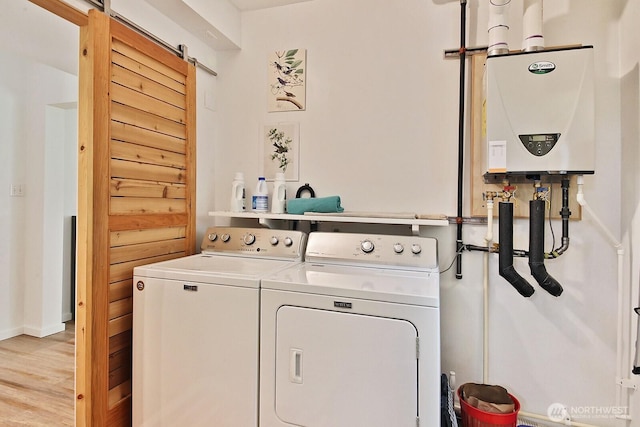 3425 Passage Way, Langley, WA 98260 - laundry room featuring tankless water heater, washing machine and dryer, a barn door, wood finished floors, and baseboards