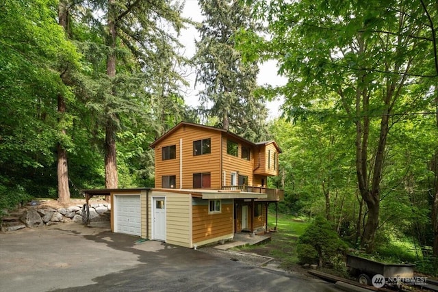 view of front facade with driveway, a garage, and a wooden deck