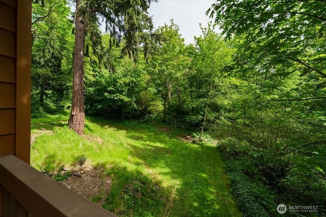 view of grassy yard featuring a view of trees