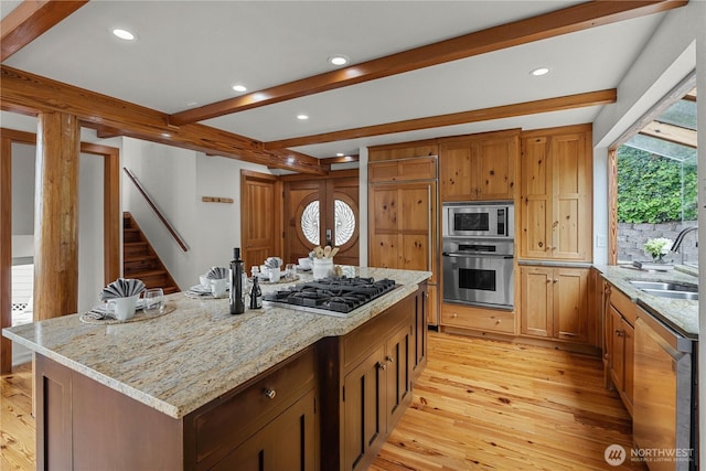 8526 E Mercer Way, Mercer Island, WA 98040 - kitchen featuring stainless steel appliances, beam ceiling, light wood-type flooring, light stone countertops, and a kitchen island