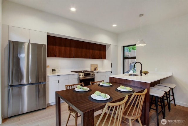 3816B 36th Ave W, Seattle, WA 98199 - kitchen featuring appliances with stainless steel finishes, a sink, light wood finished floors, light countertops, and white cabinetry