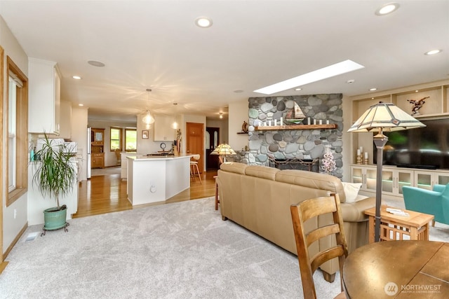 7509 145th St NW, Gig Harbor, WA 98329 - living room with light carpet, a stone fireplace, recessed lighting, and light wood-type flooring