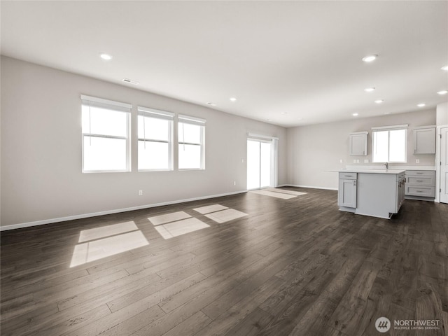 28305 74th Dr NW Unit 89, Stanwood, WA 98292 - unfurnished living room featuring plenty of natural light, baseboards, recessed lighting, and dark wood-style floors