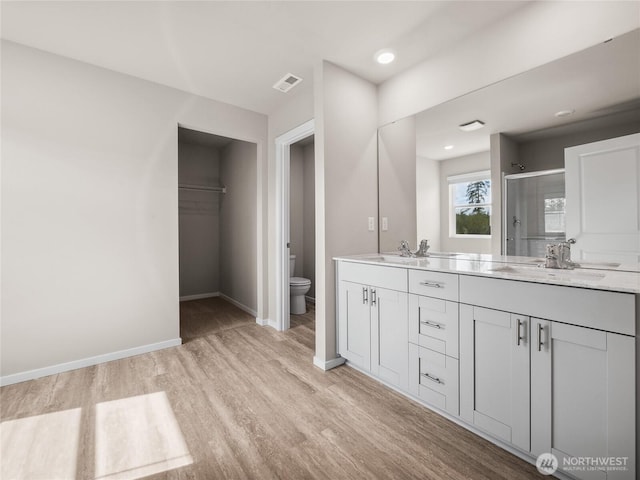 28305 74th Dr NW Unit 89, Stanwood, WA 98292 - bathroom featuring toilet, wood finished floors, double vanity, a stall shower, and baseboards