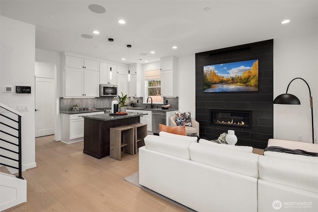 living area featuring recessed lighting, light wood-type flooring, and a large fireplace