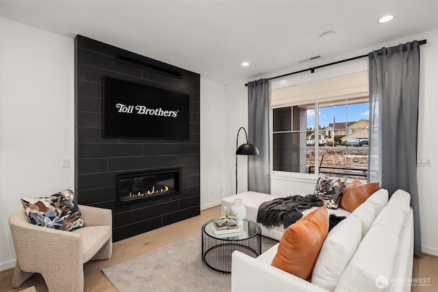 living area featuring wood finished floors, a large fireplace, and recessed lighting