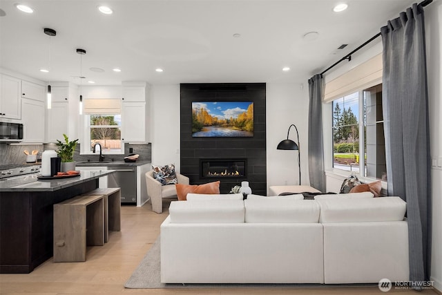 living room with light wood-style flooring, recessed lighting, and a fireplace