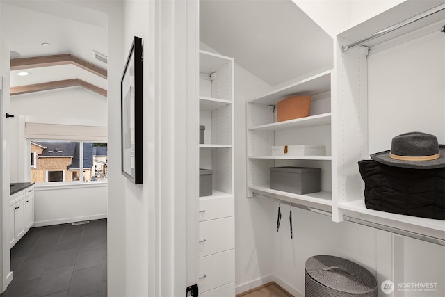 walk in closet with lofted ceiling and dark tile patterned flooring