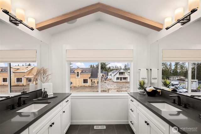 bathroom featuring vaulted ceiling, two vanities, and tile patterned flooring