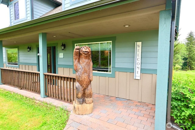 view of exterior entry with covered porch and board and batten siding
