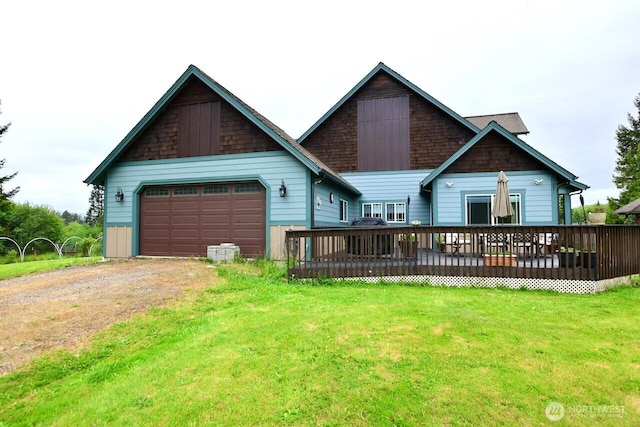 view of front of home featuring driveway, a garage, a deck, and a front lawn