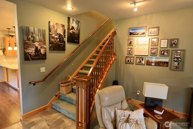 staircase featuring baseboards and rail lighting