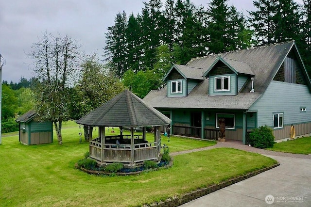 view of front of property featuring a gazebo, a porch, a front lawn, a storage shed, and a shingled roof