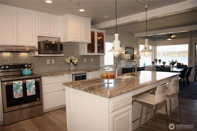 5341 S Bercot Rd, Freeland, WA 98249 - kitchen featuring appliances with stainless steel finishes, under cabinet range hood, wood finished floors, backsplash, and white cabinets
