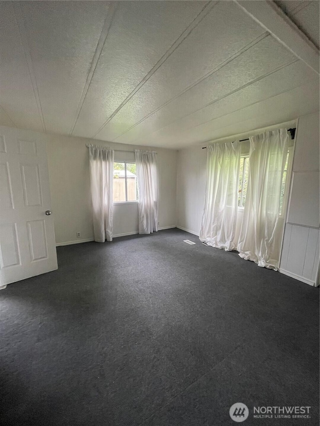 1050 Howard St Unit 10, Raymond, WA 98577 - spare room with baseboards, dark colored carpet, and a textured ceiling