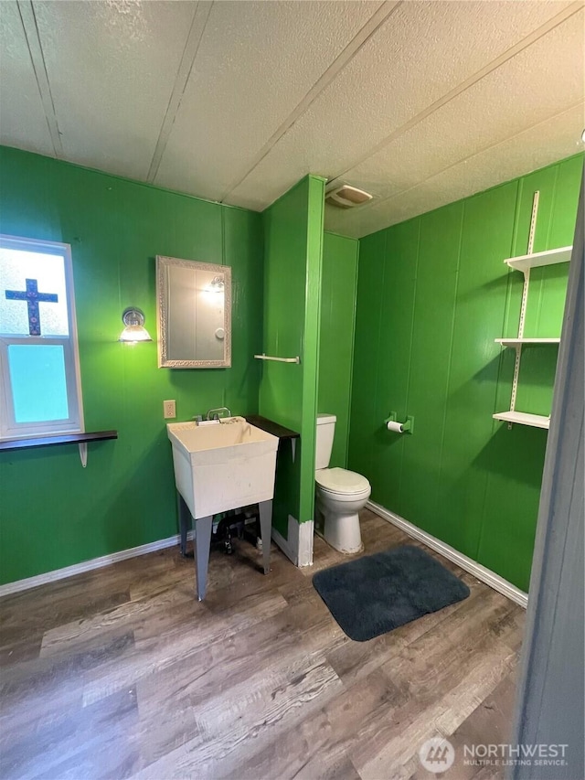 1050 Howard St Unit 10, Raymond, WA 98577 - bathroom featuring wood finished floors, a textured ceiling, toilet, and baseboards