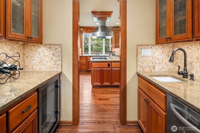 kitchen featuring stainless steel dishwasher, wine cooler, a sink, wood finished floors, and light stone counters
